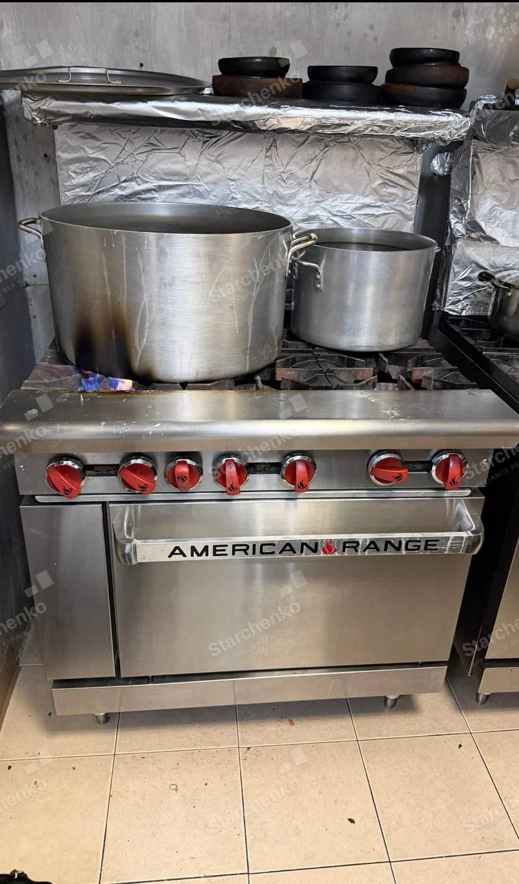 AMERICAN RANGE wordmark across oven-door handle on heavy-duty range with pots over burners.