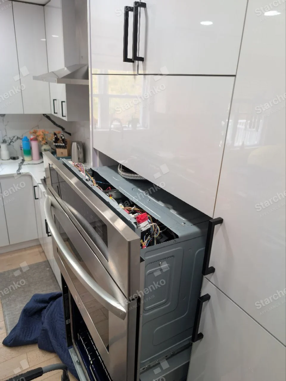 Whirlpool repair: Upper unit of stacked wall ovens pulled forward with top control panel and wiring exposed.