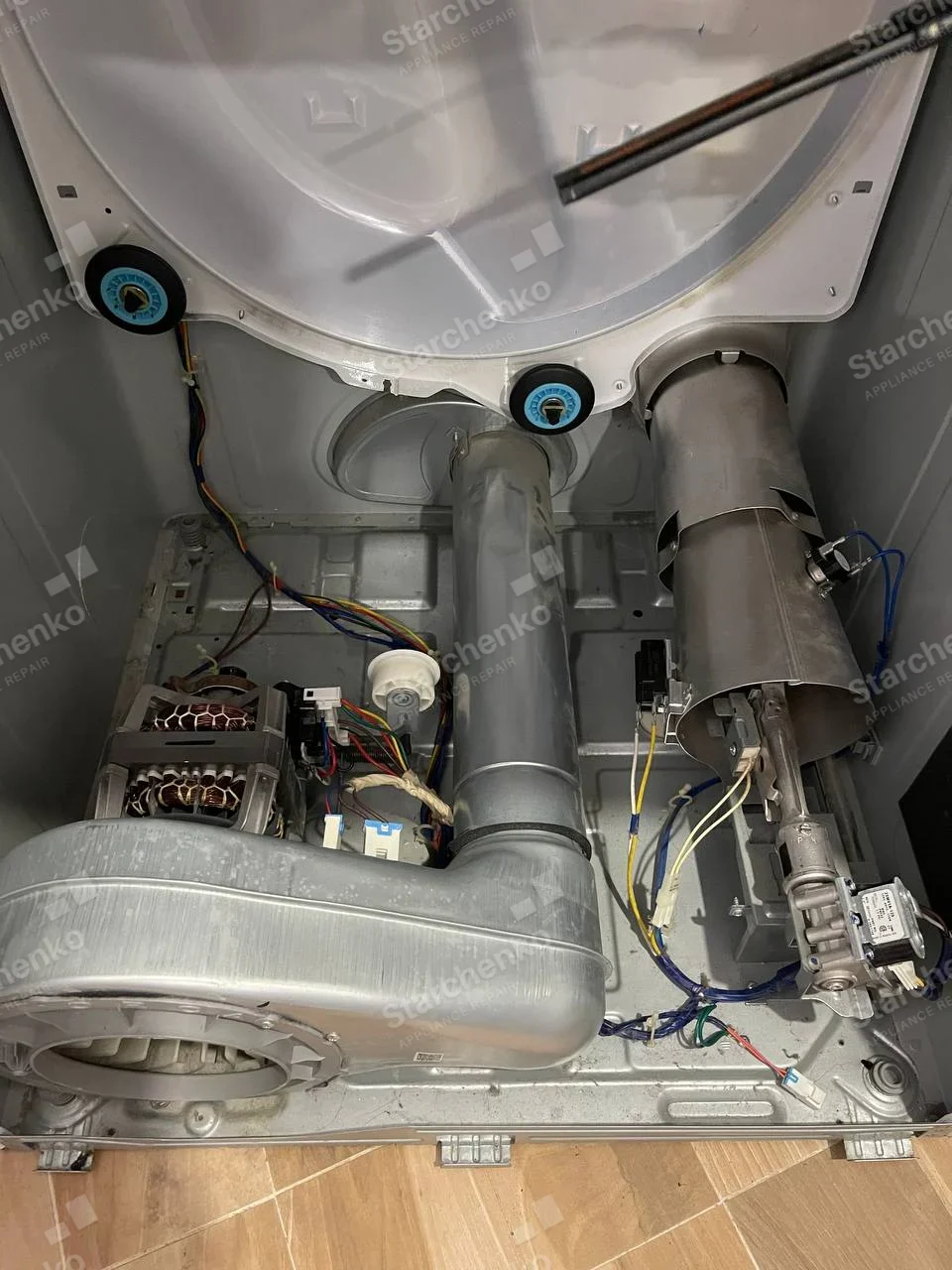 Whirlpool repair: Front-load dryer cabinet opened from rear or lower panel showing blower, motor, exhaust duct and heater tube.