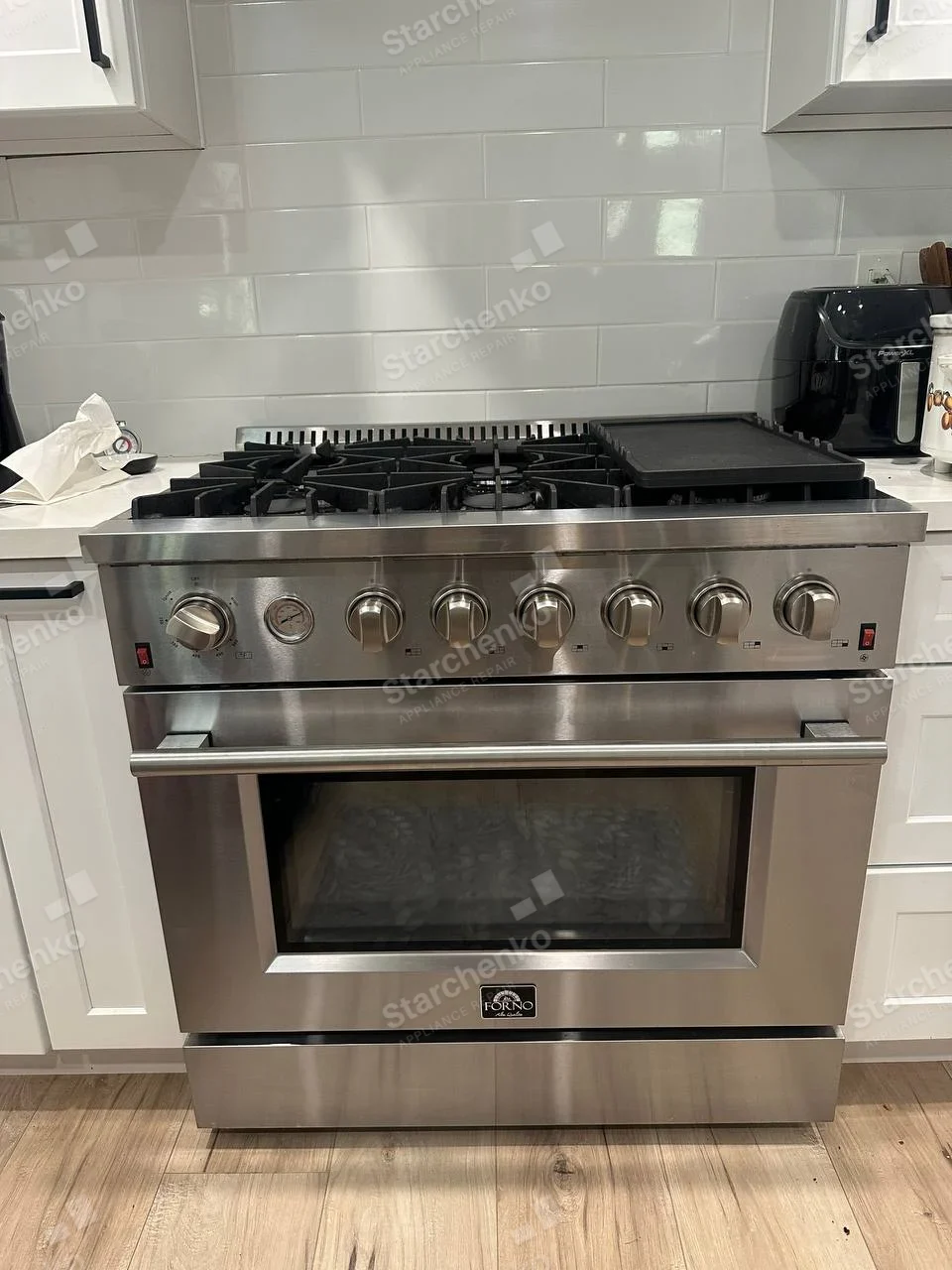 FORNO badge centered on oven door of main gas range with griddle and burners.