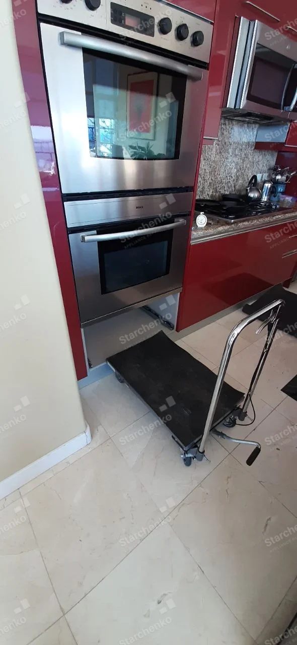 Bosch built-in microwave below separate wall oven with service dolly positioned beneath.