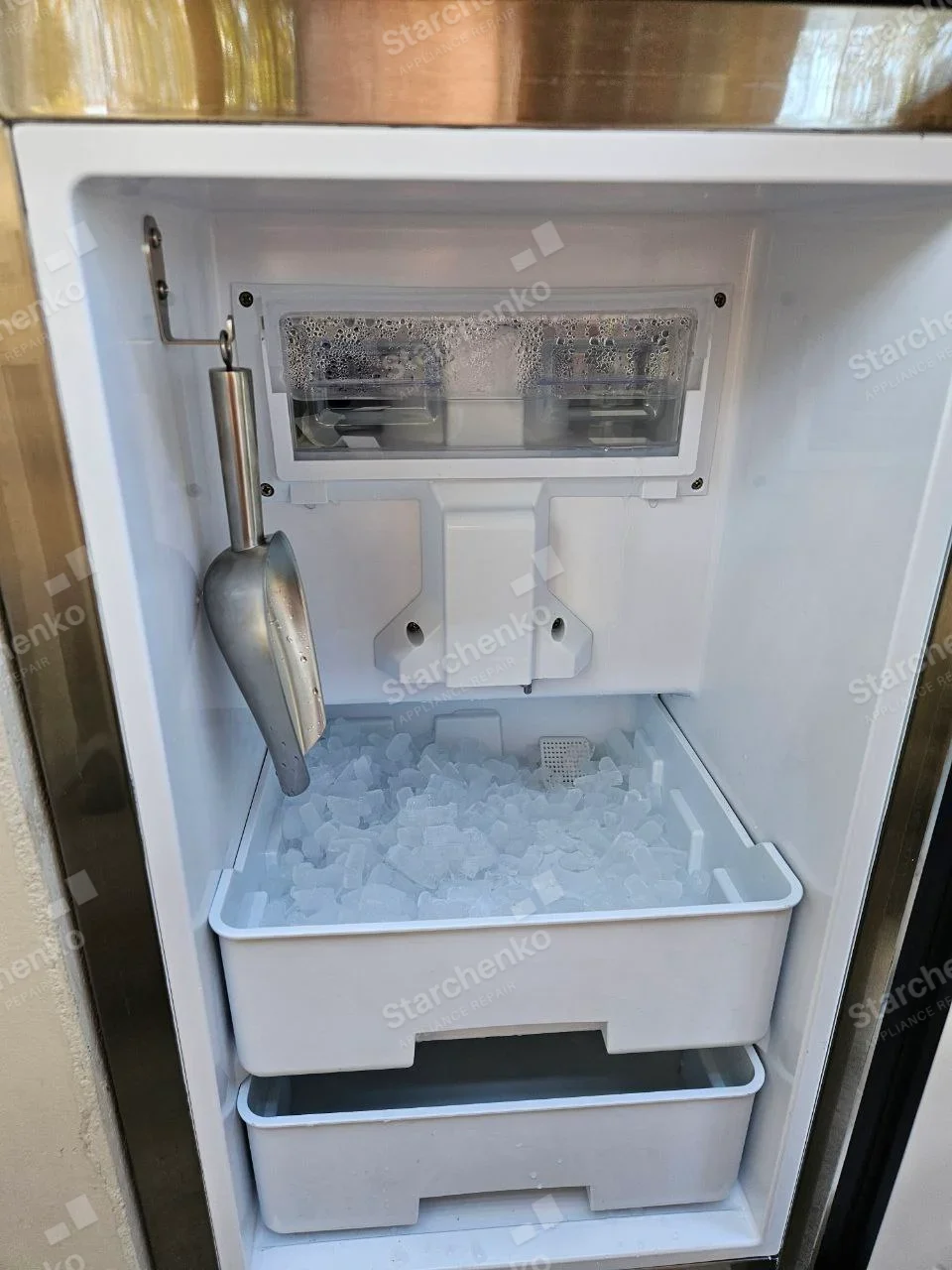 Whirlpool repair: Ice bin and evaporator inside standalone undercounter ice maker, clear ice in upper bin, no manufacturer mark.