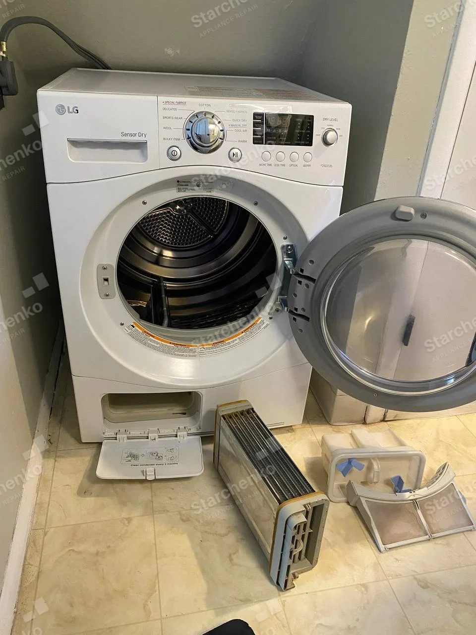 LG logo on upper-left dryer control panel, lint filter and lower front duct/filter parts removed and placed in front.