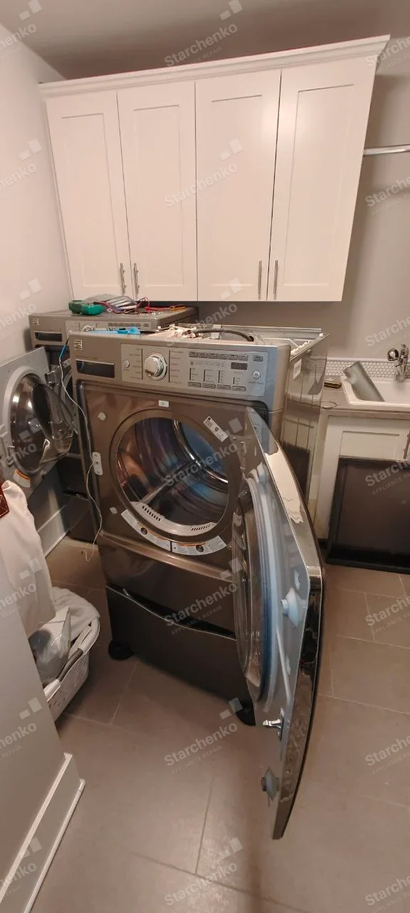 GE repair: Central front-load dryer with drum and open door, top service panel removed.