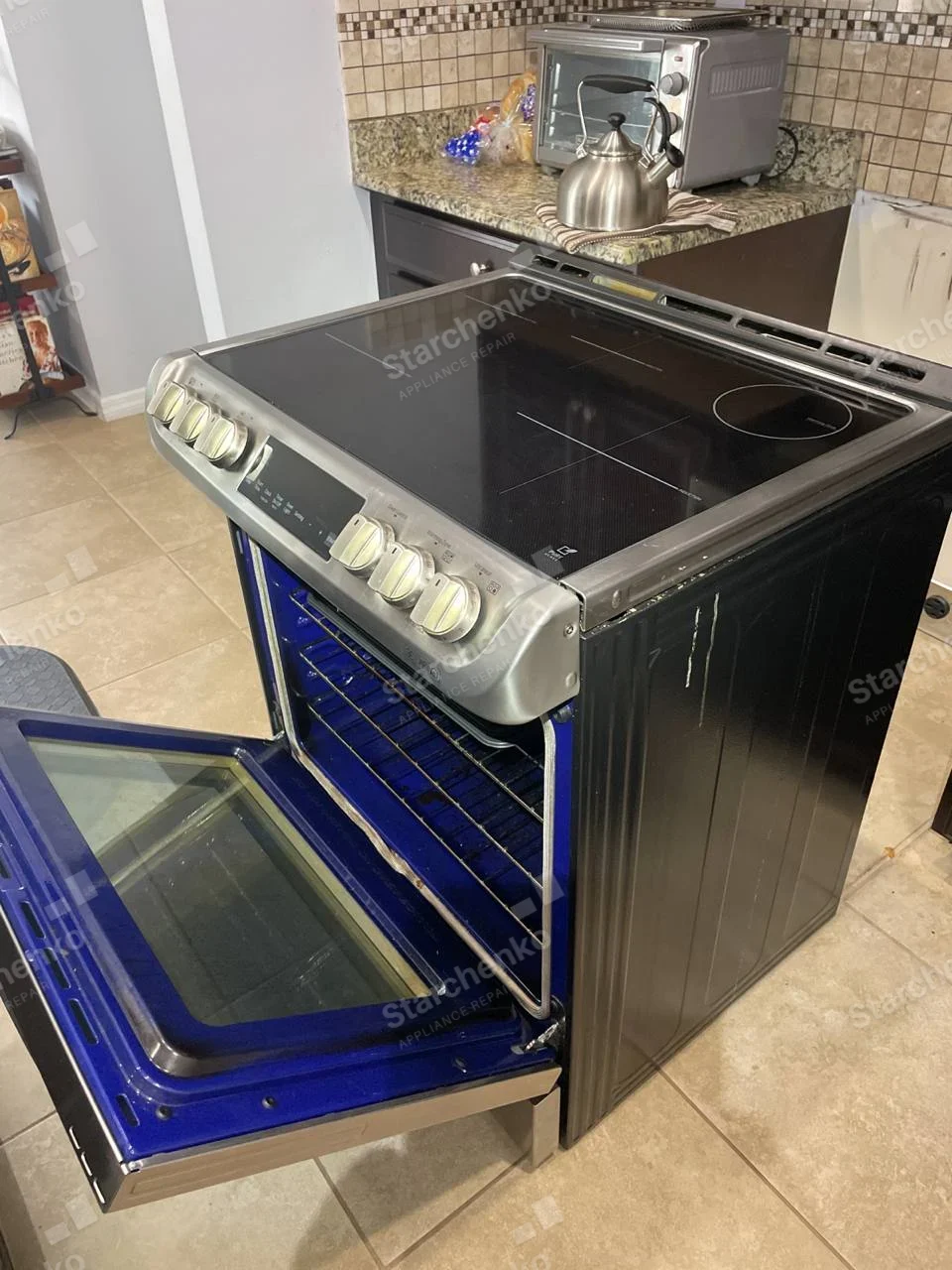 LG electric smooth-top range pulled out with its blue oven cavity visible through an open door.