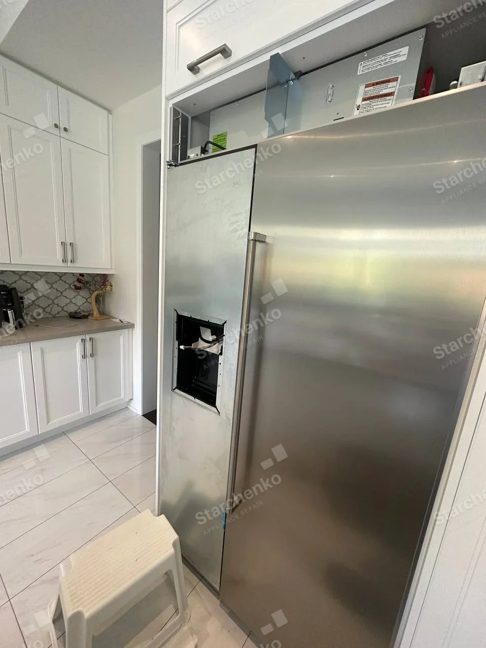 Frigidaire repair: Stainless side-by-side refrigerator with dispenser module removed from the left door and exposed wiring.