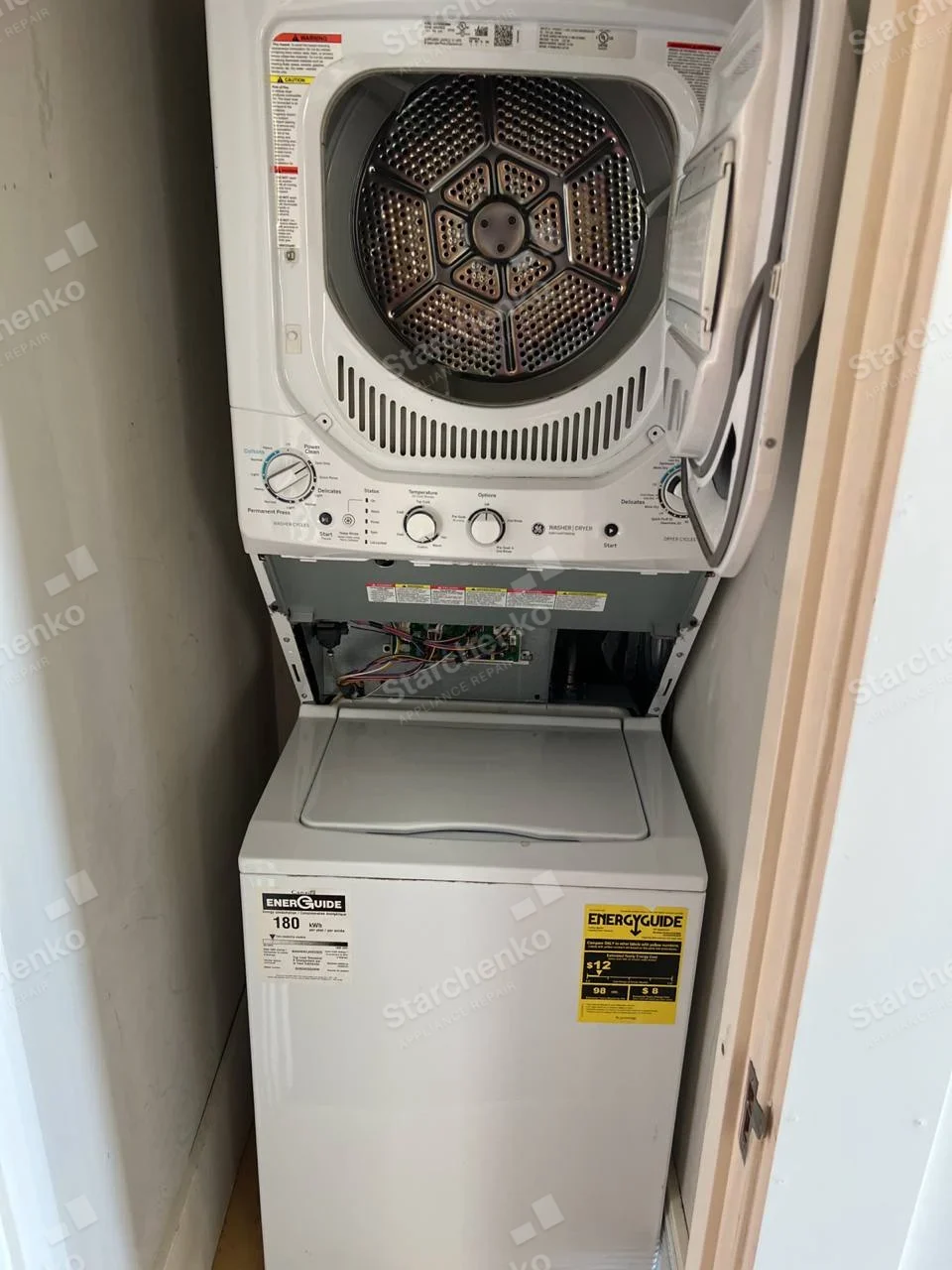 GE stacked dryer with door open and control wiring exposed above a top-load washer.