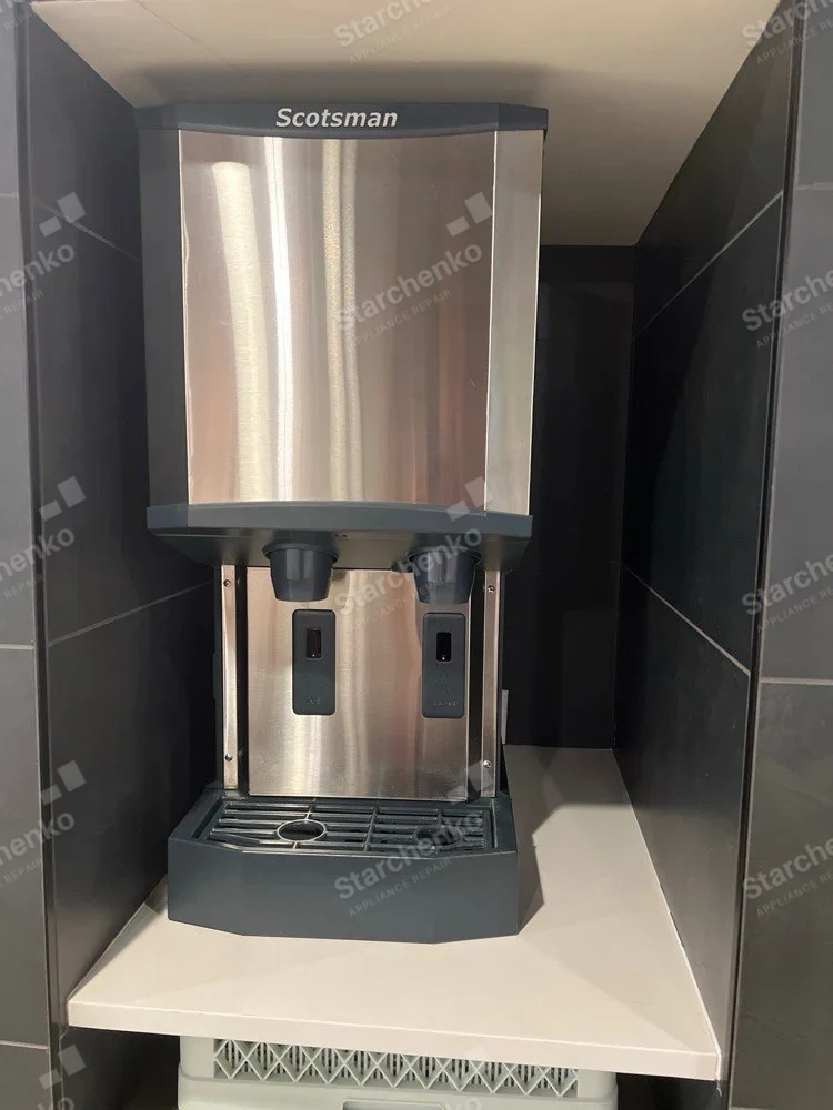 Scotsman lettering across top front of freestanding countertop unit with two dispensing spouts and drip tray.
