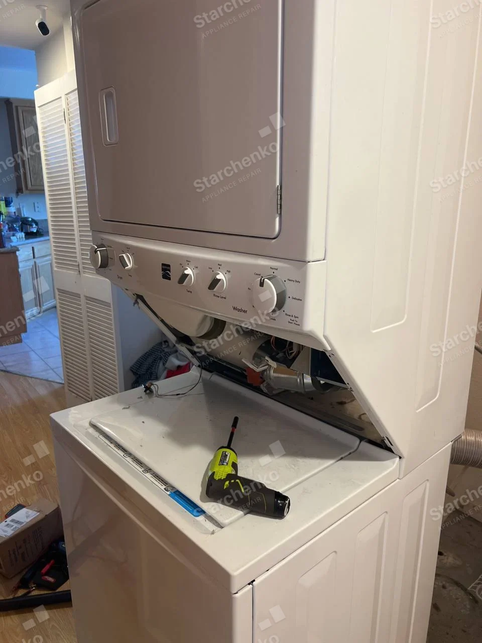 Kenmore repair: Stacked dryer and washer with front access panel open between the two units.