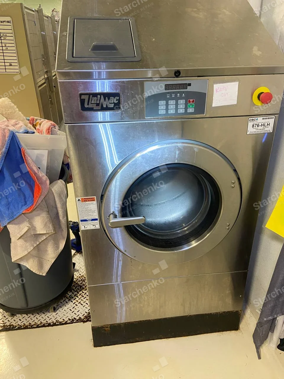 Stainless UniMac commercial front-load washer with keypad and round door.