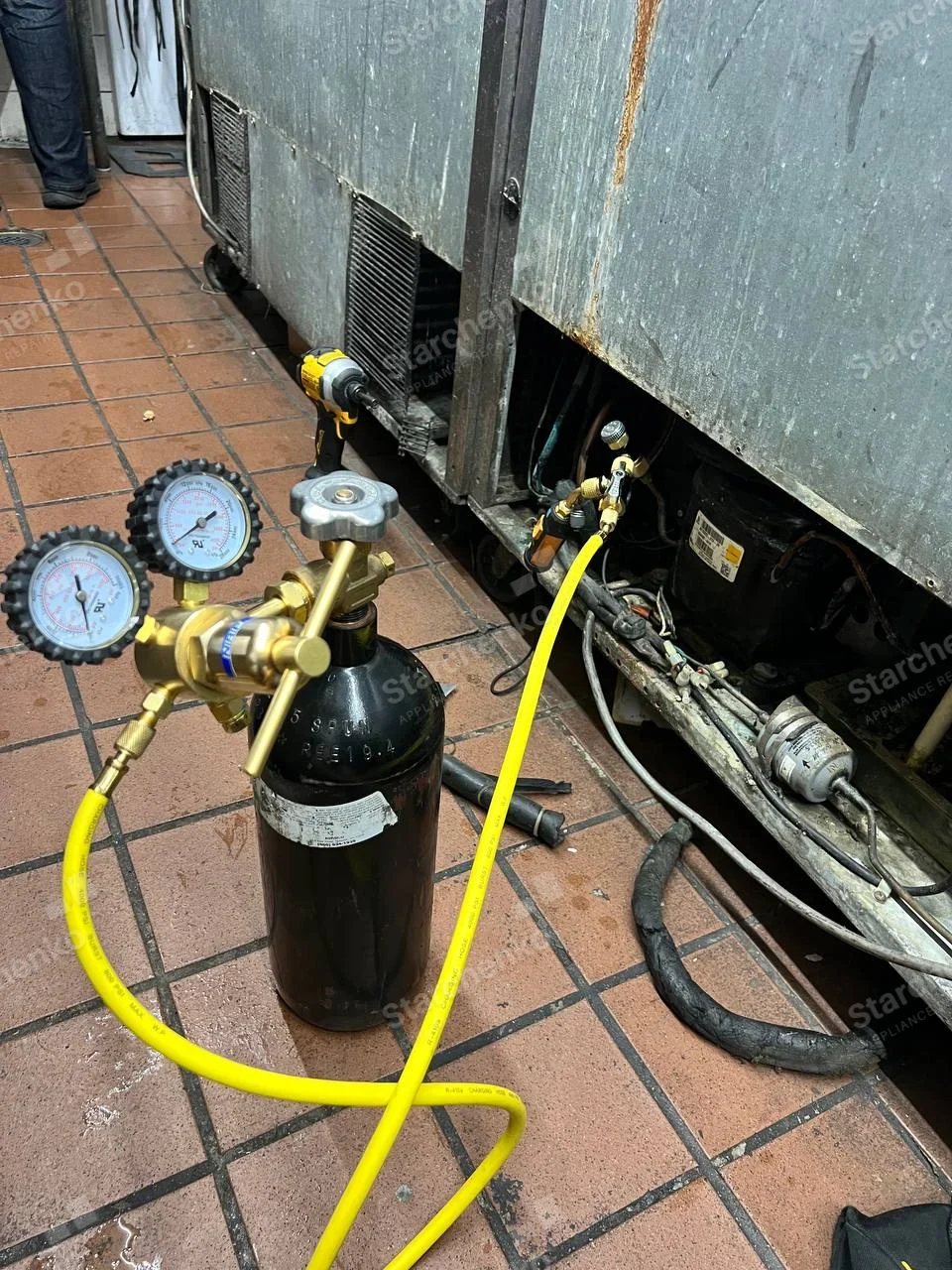 Everest repair: Commercial refrigeration cabinet base opened at compressor and charging port, upper form outside frame, no manufacturer mark.