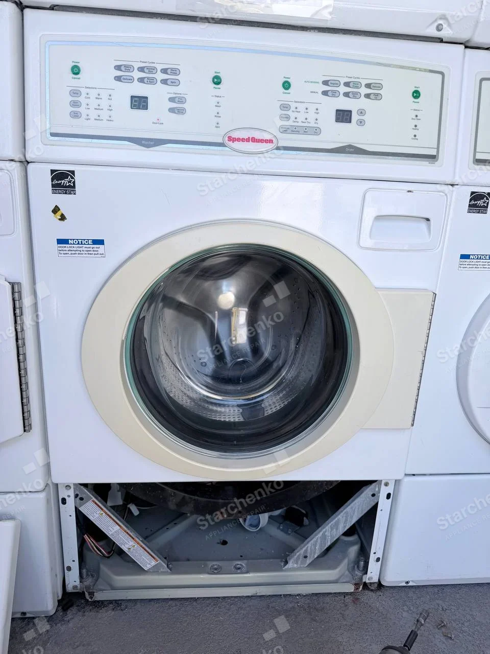 Speed Queen wordmark centered on shared control fascia, open lower panel belongs to the washer, while dryer is above/outside frame.