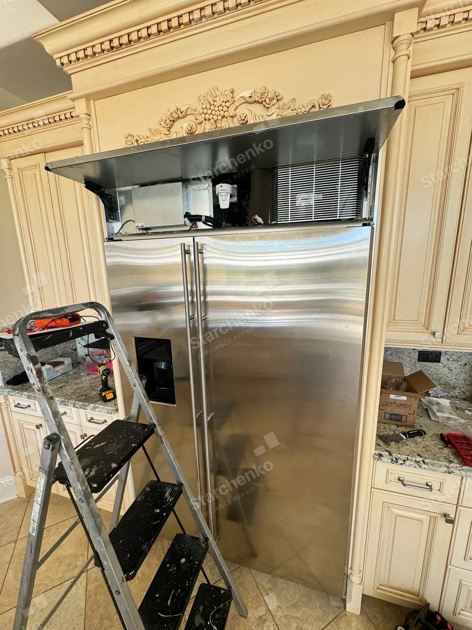 GE Monogram repair: Built-in stainless side-by-side refrigerator with upper cooling and electronics compartment open.