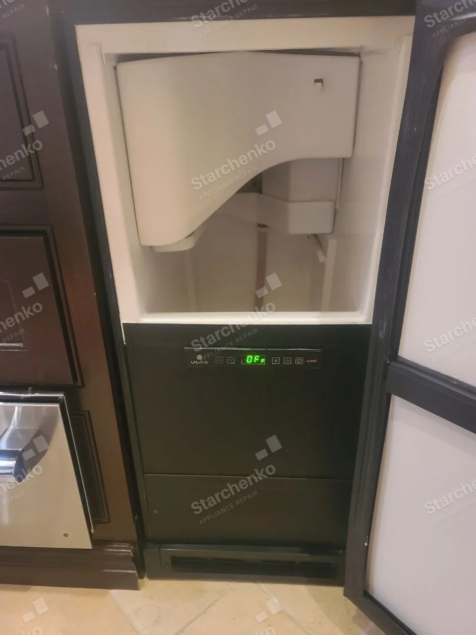Black U-Line undercounter ice maker with open bin and front control display reading OF.