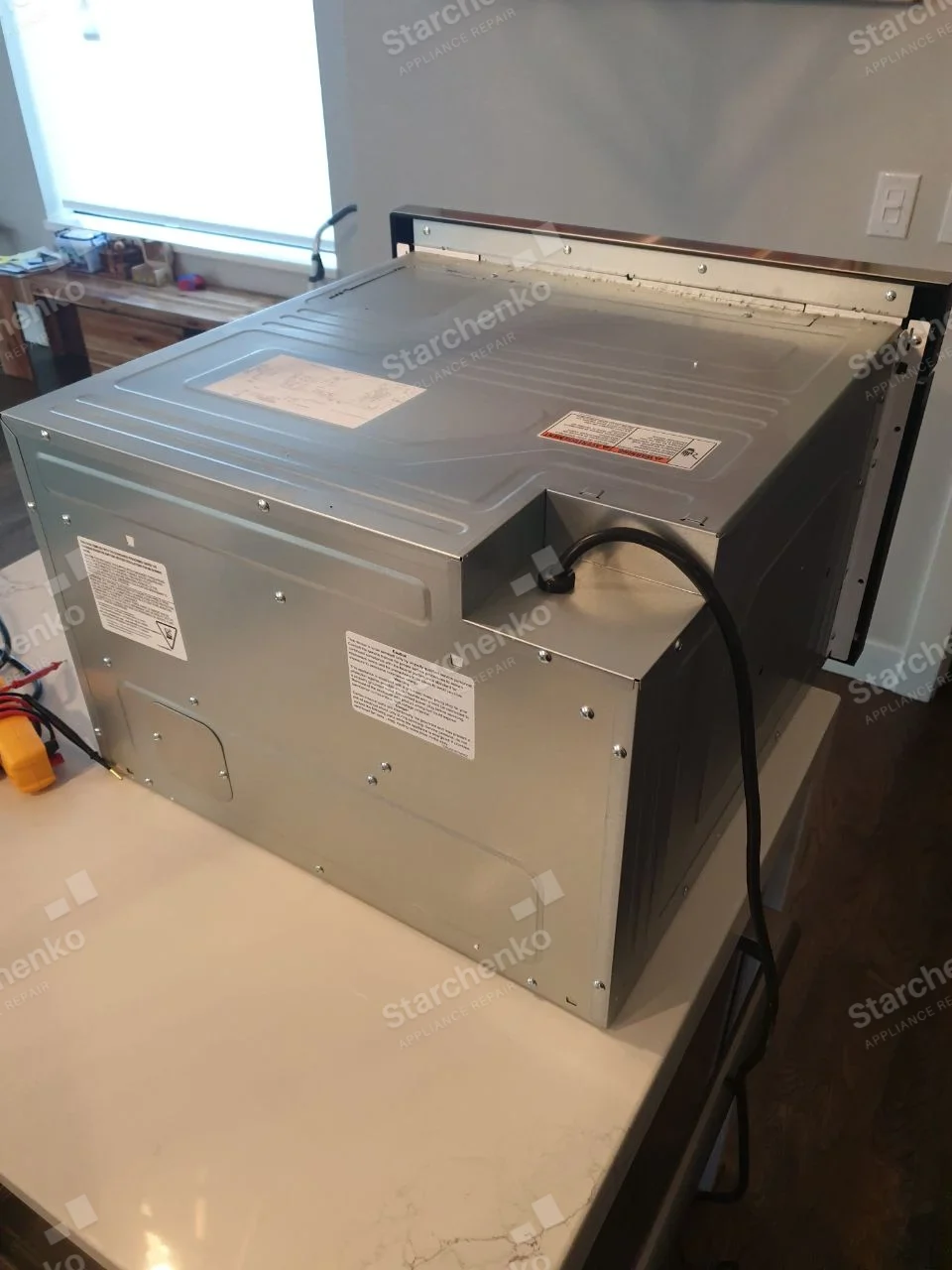 Samsung repair: Back and top of over-the-range microwave resting on a kitchen counter after removal.