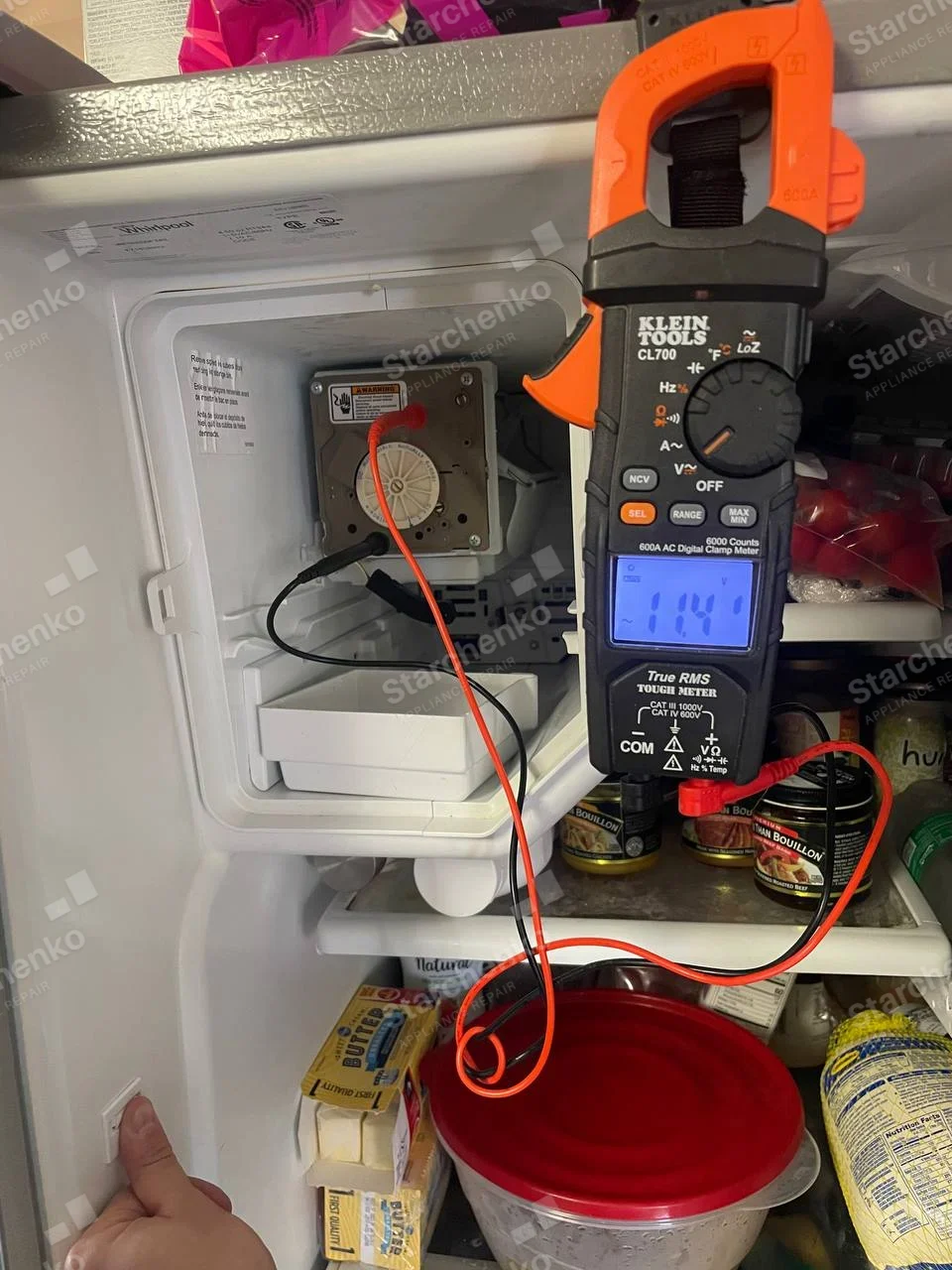 Whirlpool printed on refrigerator interior label above exposed freezer ice-maker, probes checking ice-maker motor.