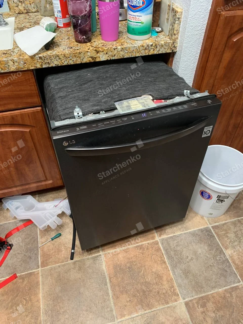 Black LG dishwasher pulled out from under the counter with top frame and sound blanket visible.