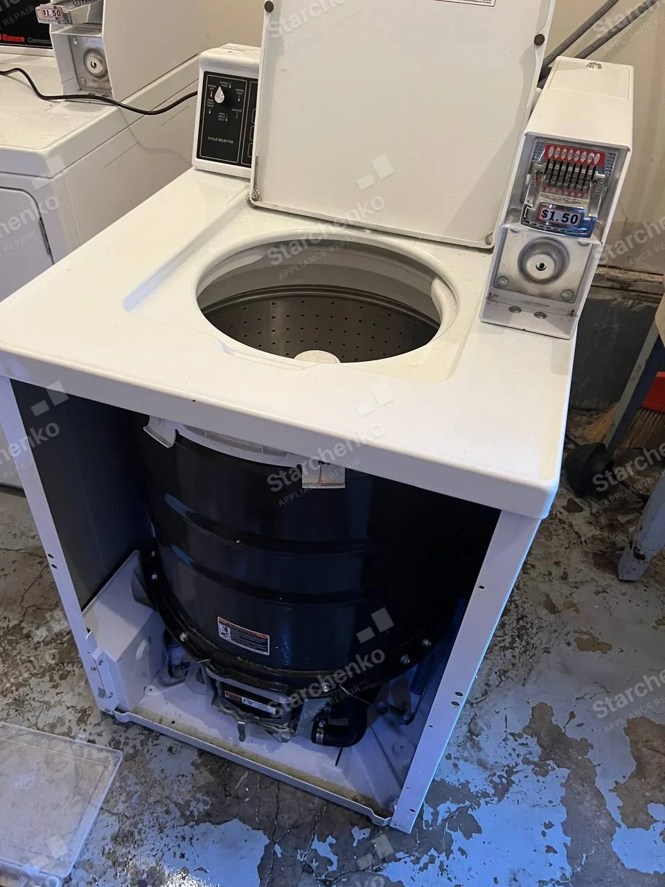 GE repair: Top-loading washer with coin slide marked $1.50 and front casing removed, exposing the tub.