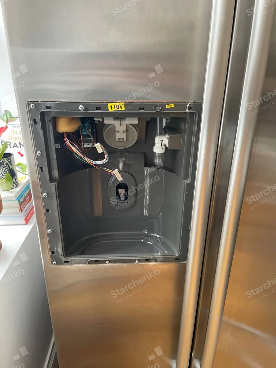 Frigidaire repair: Stainless side-by-side refrigerator door with ice/water dispenser housing exposed and controls disconnected.