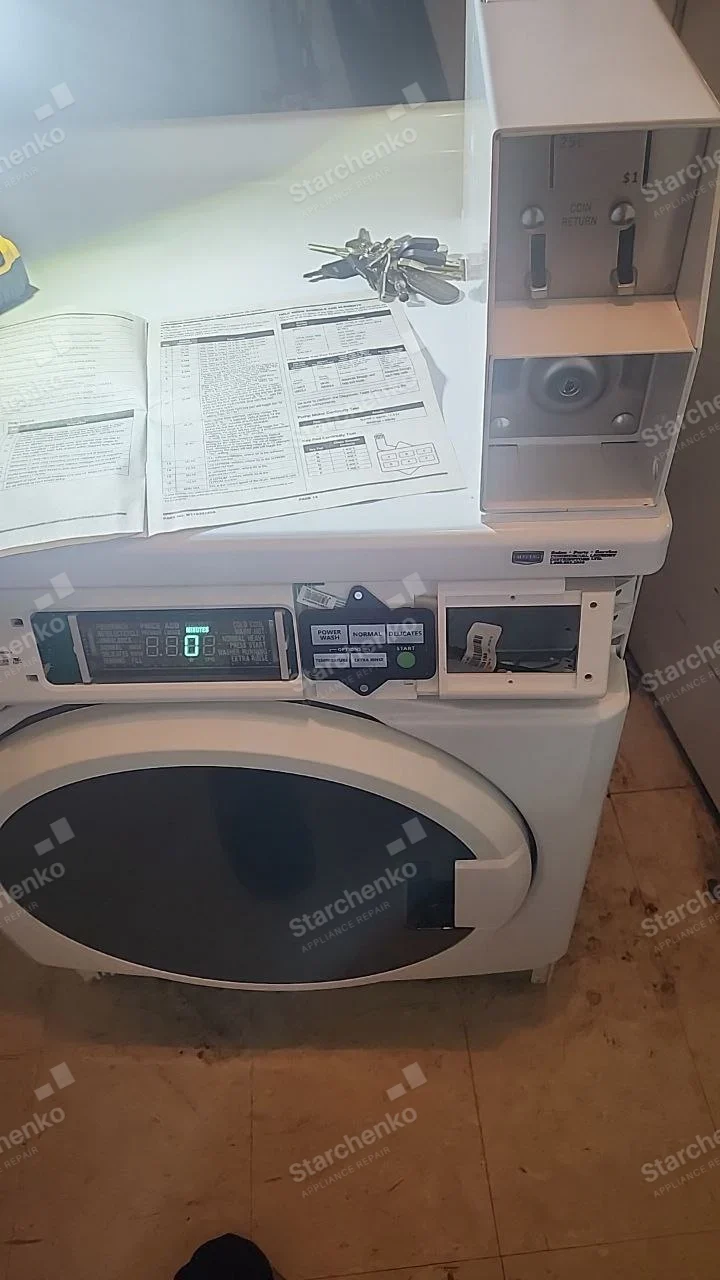 Huebsch repair: Coin-operated front-load washer with digital wash controls and coin housing open.