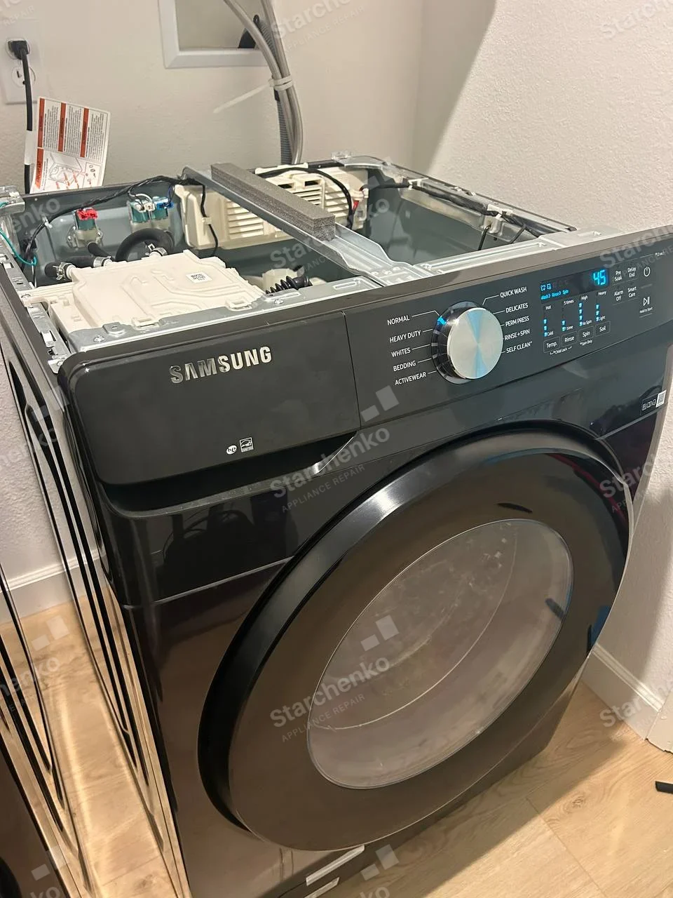 SAMSUNG lettering on upper-left washer fascia, front-load door and exposed top tub components.