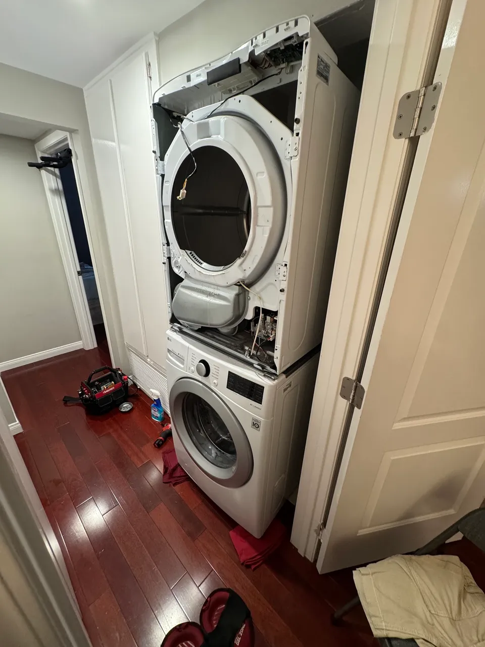 Stacked washer-dryer in a hallway closet with the dryer front opened