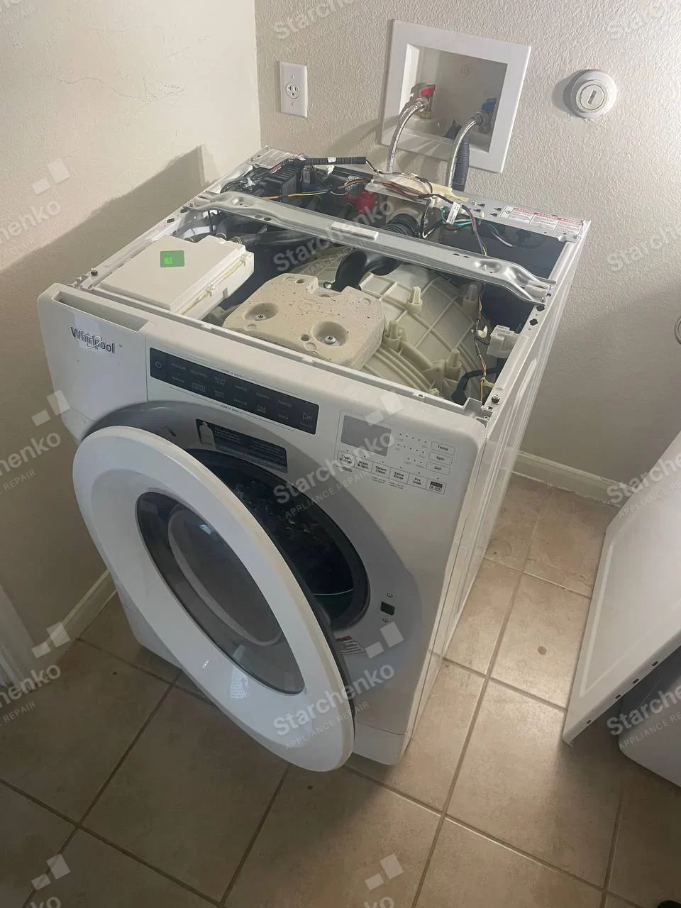 Whirlpool repair: Front-load washer with top panel off exposing tub, counterweight and electronic module.