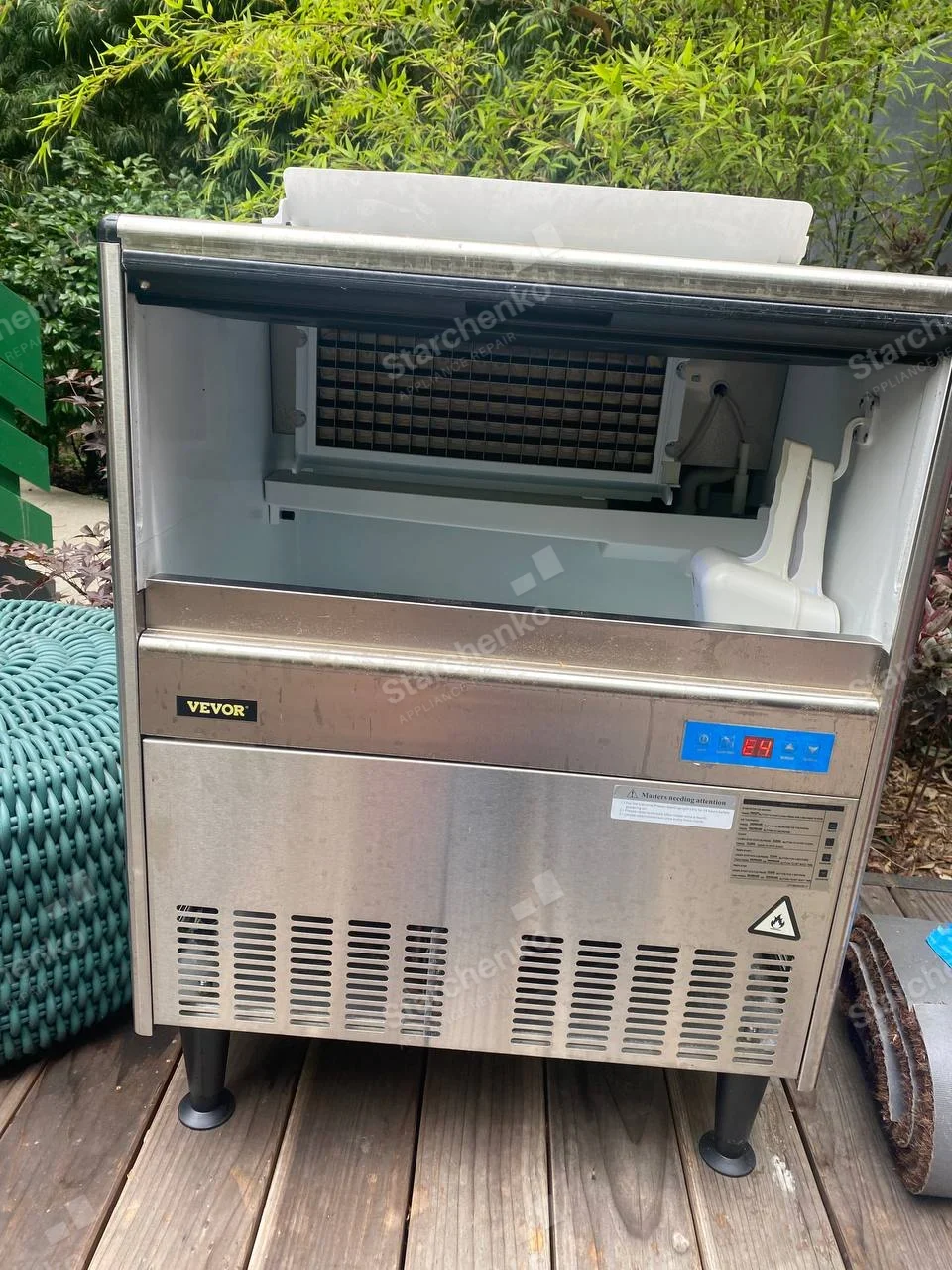 VEVOR stainless ice machine with open upper compartment showing ice grid and chute.