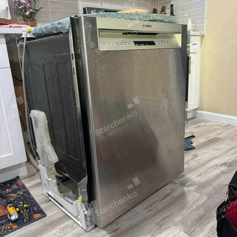 Bosch repair: Dishwasher pulled out from cabinet, with side panel and lower mechanisms exposed.