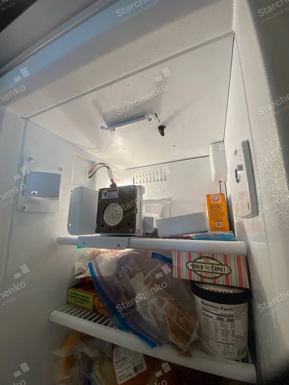 Whirlpool repair: Inside domestic freezer, ice-maker assembly detached and resting on shelf, no refrigerator maker mark.
