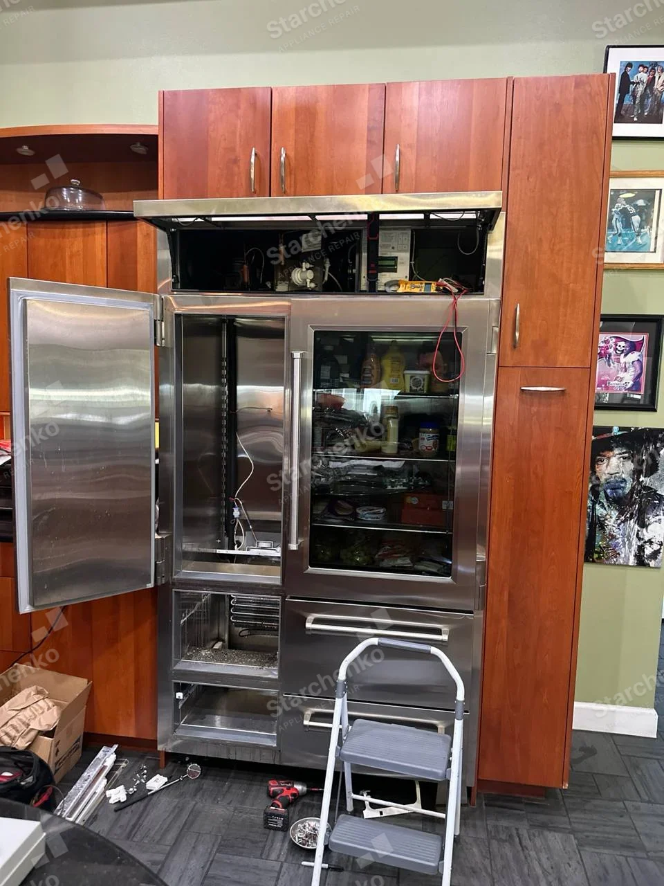 GE Monogram repair: Tall stainless built-in refrigeration unit, left compartment open and upper service panel removed with test leads attached.