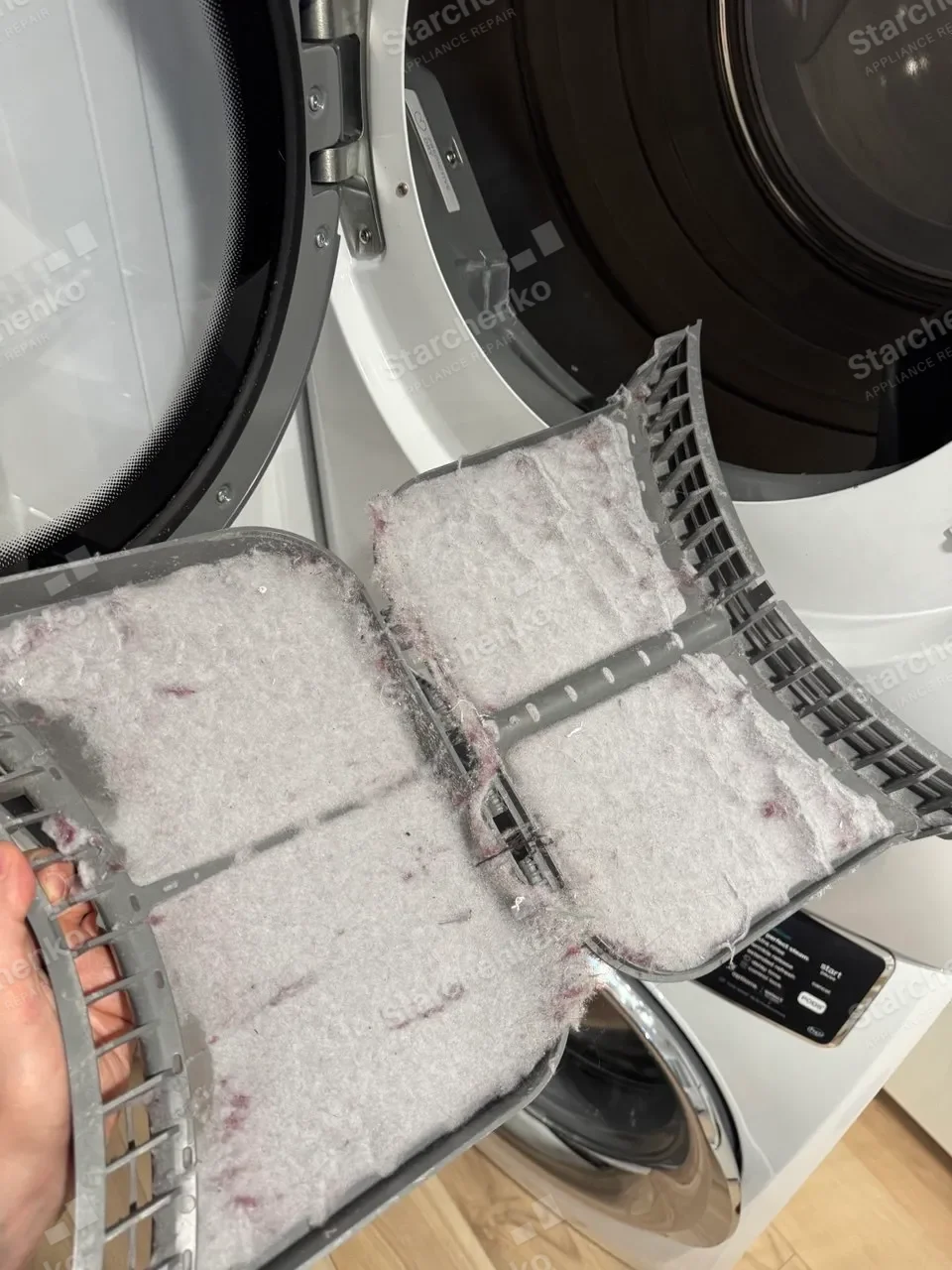 Dryer lint filter packed solid with lint, held up in front of the open door