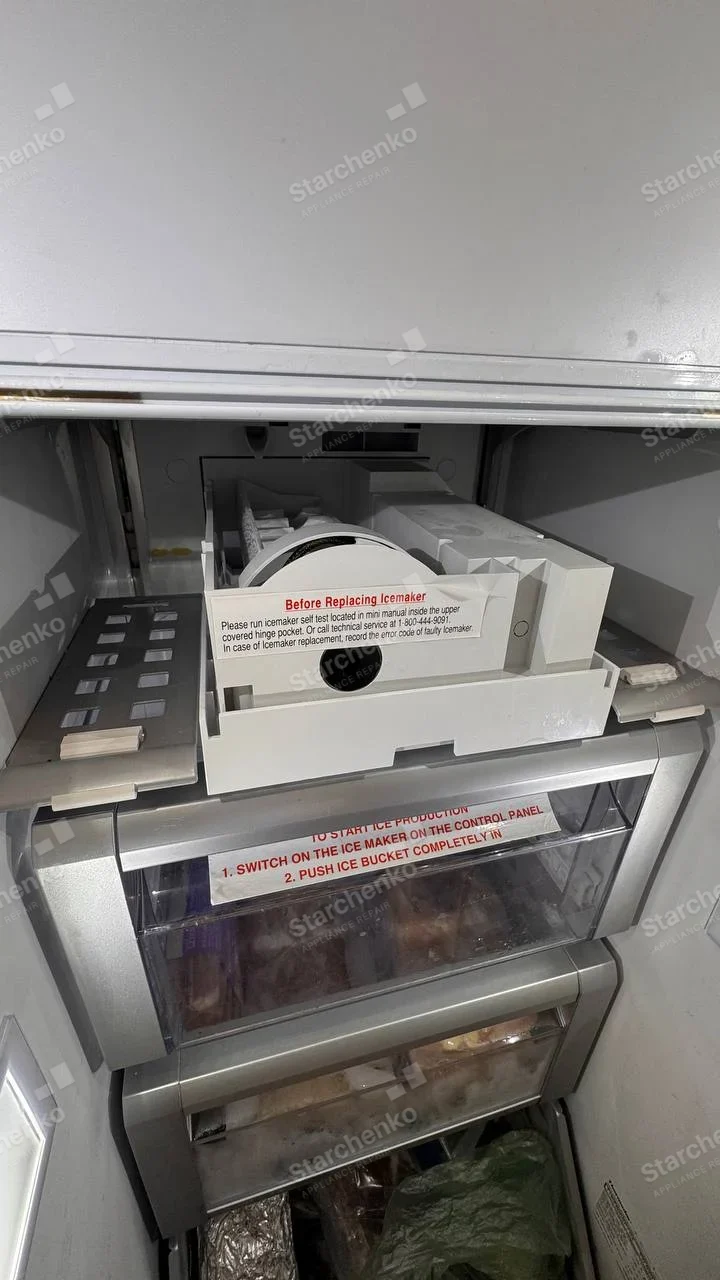 Whirlpool repair: Freezer ice-maker mechanism and bucket partially pulled forward inside refrigerator, service instruction sticker has no maker identity.