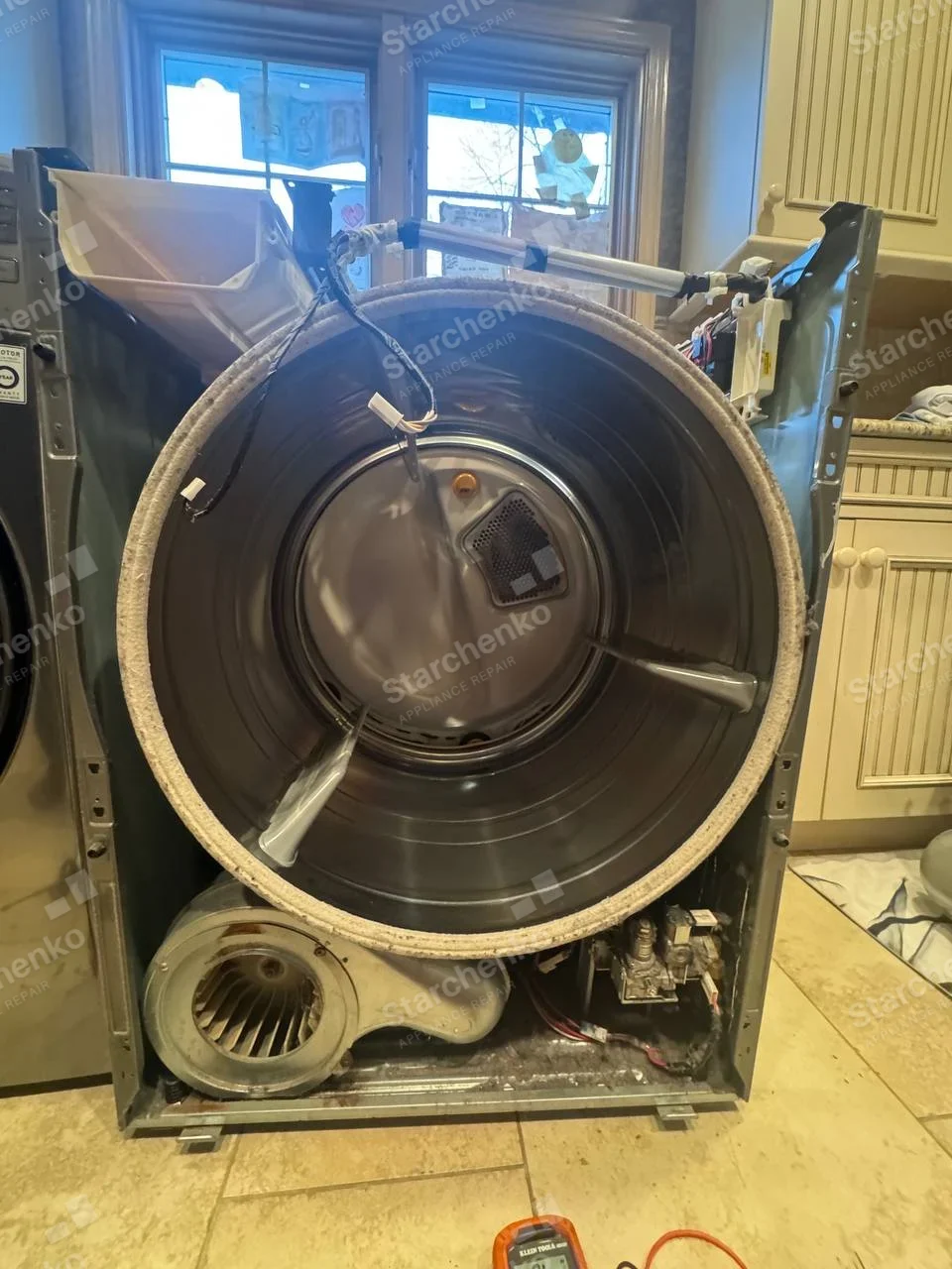GE repair: Dryer front removed, drum and blower open.