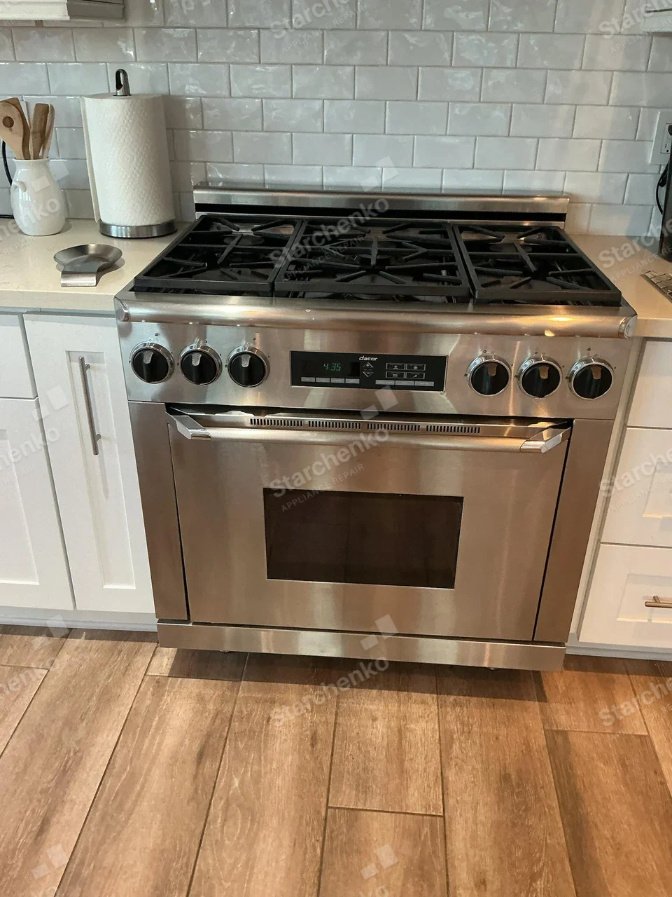 Dacor name on central control display of six-burner gas range with oven below.