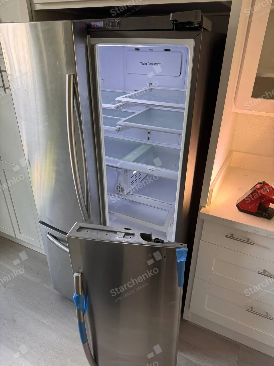 Samsung French-door refrigerator with right fresh-food door detached and resting in front.