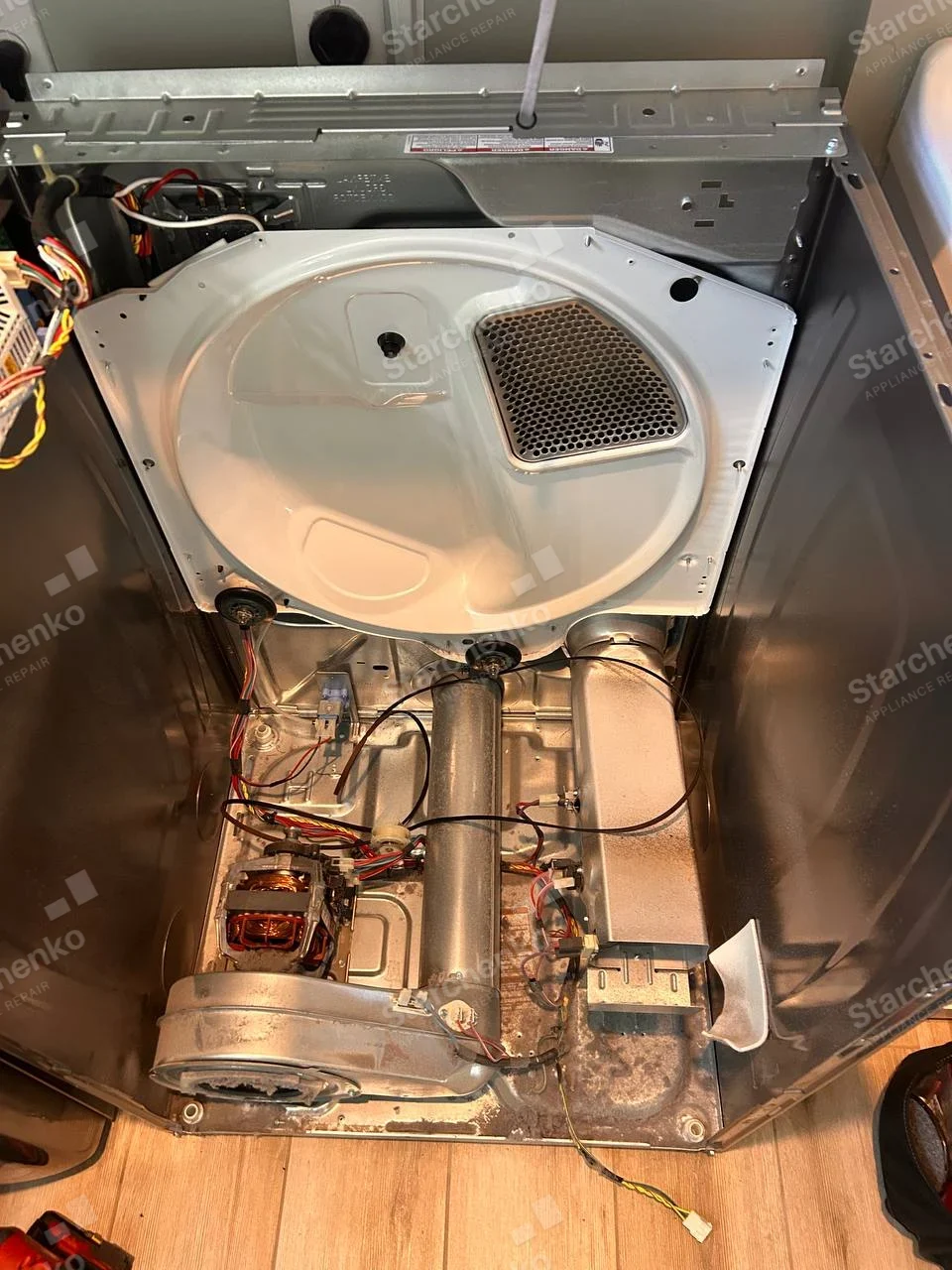 GE repair: Rear of dryer open, showing drum, motor, blower and heating assembly.