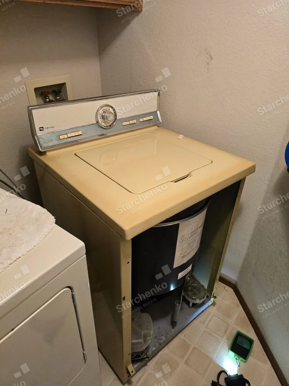 Maytag name on left control console, washer front panel removed revealing tub and drive.