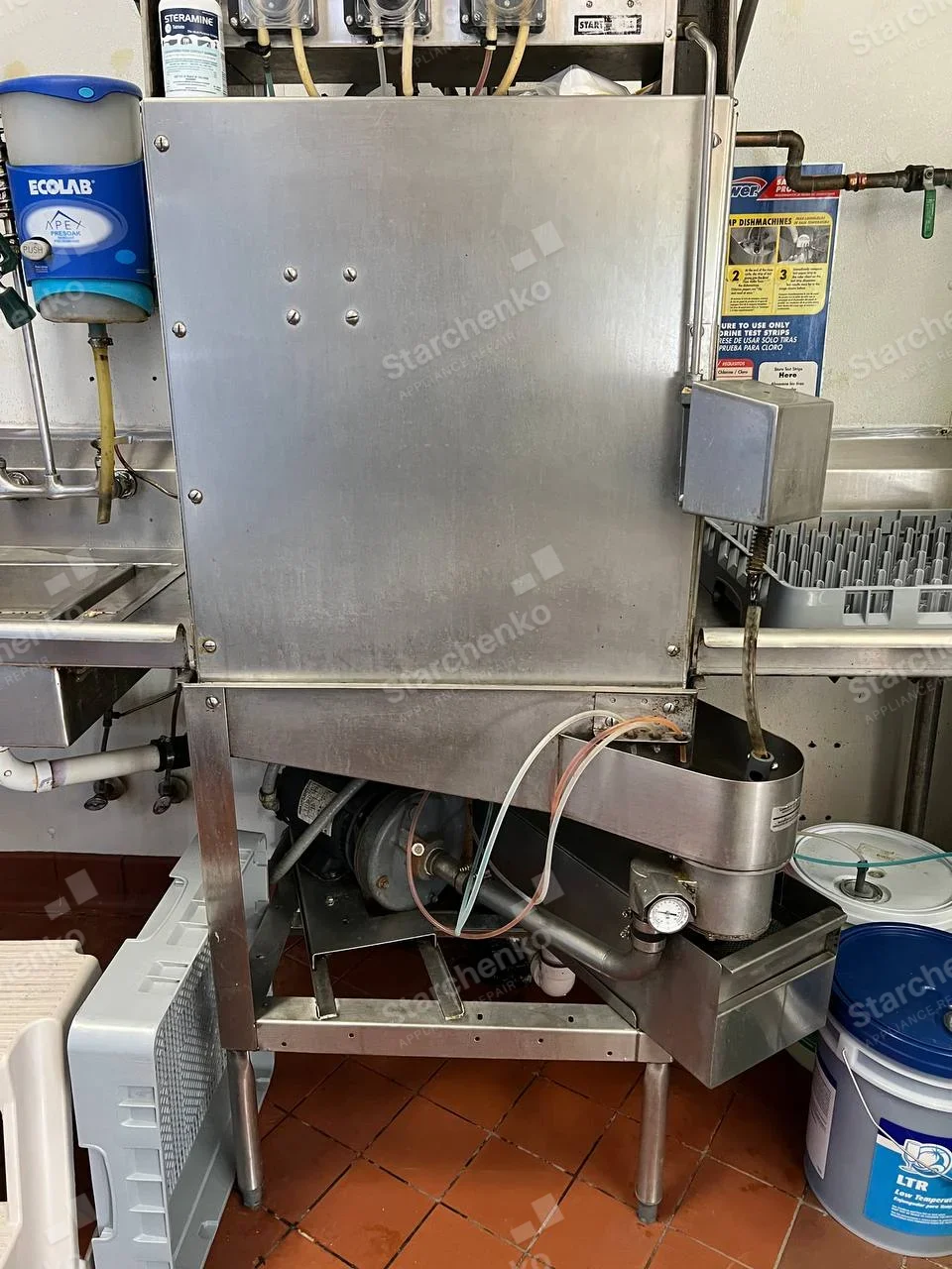 Moyer Diebel repair: Rear of tall commercial dishwasher with pump, hoses and chemical dosing lines visible.