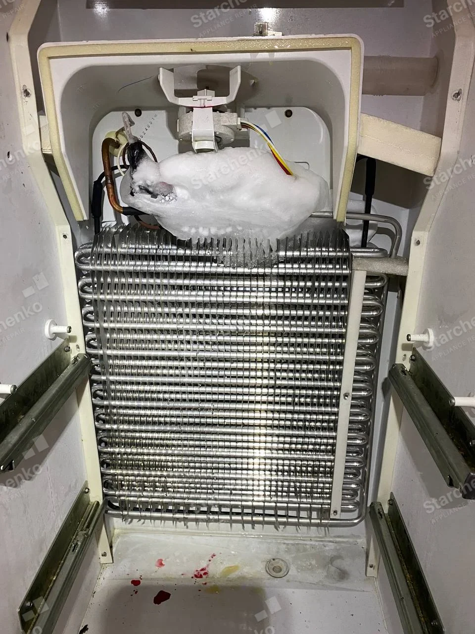 Whirlpool repair: Freezer interior with rear panel off, exposed evaporator coil and ice accumulation around upper assembly.