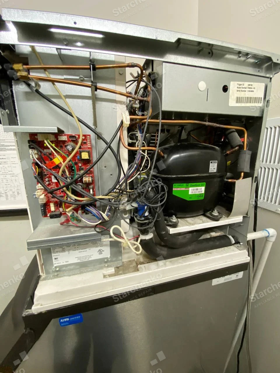 Kold-Draft repair: Open commercial ice machine head above storage bin, showing compressor, control board and tubing.