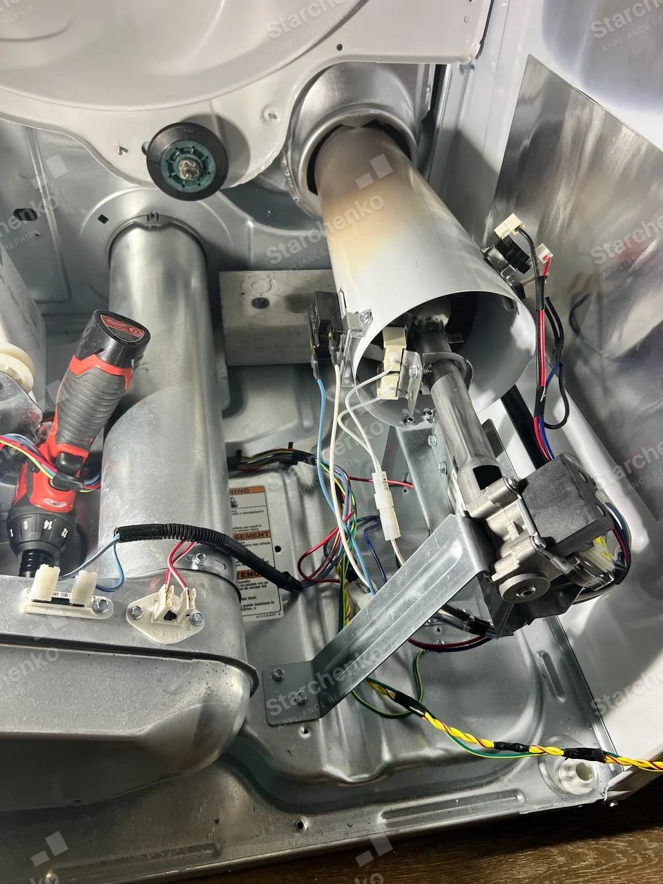Maytag repair: Dryer interior exposed with blower duct and motor assembly.
