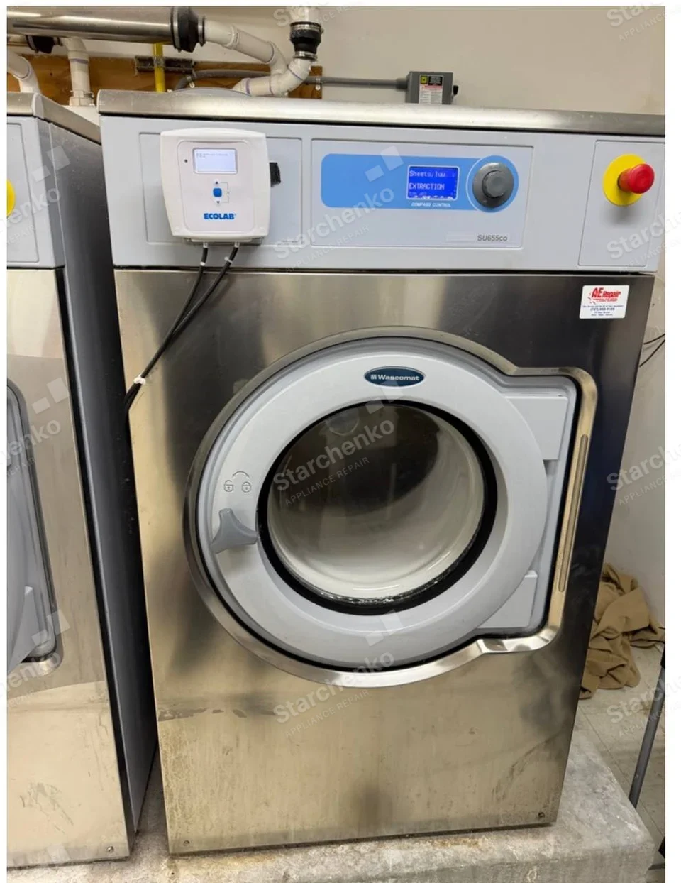 Wascomat oval logo on main front-loading industrial washer door, Ecolab dispenser is separate add-on.