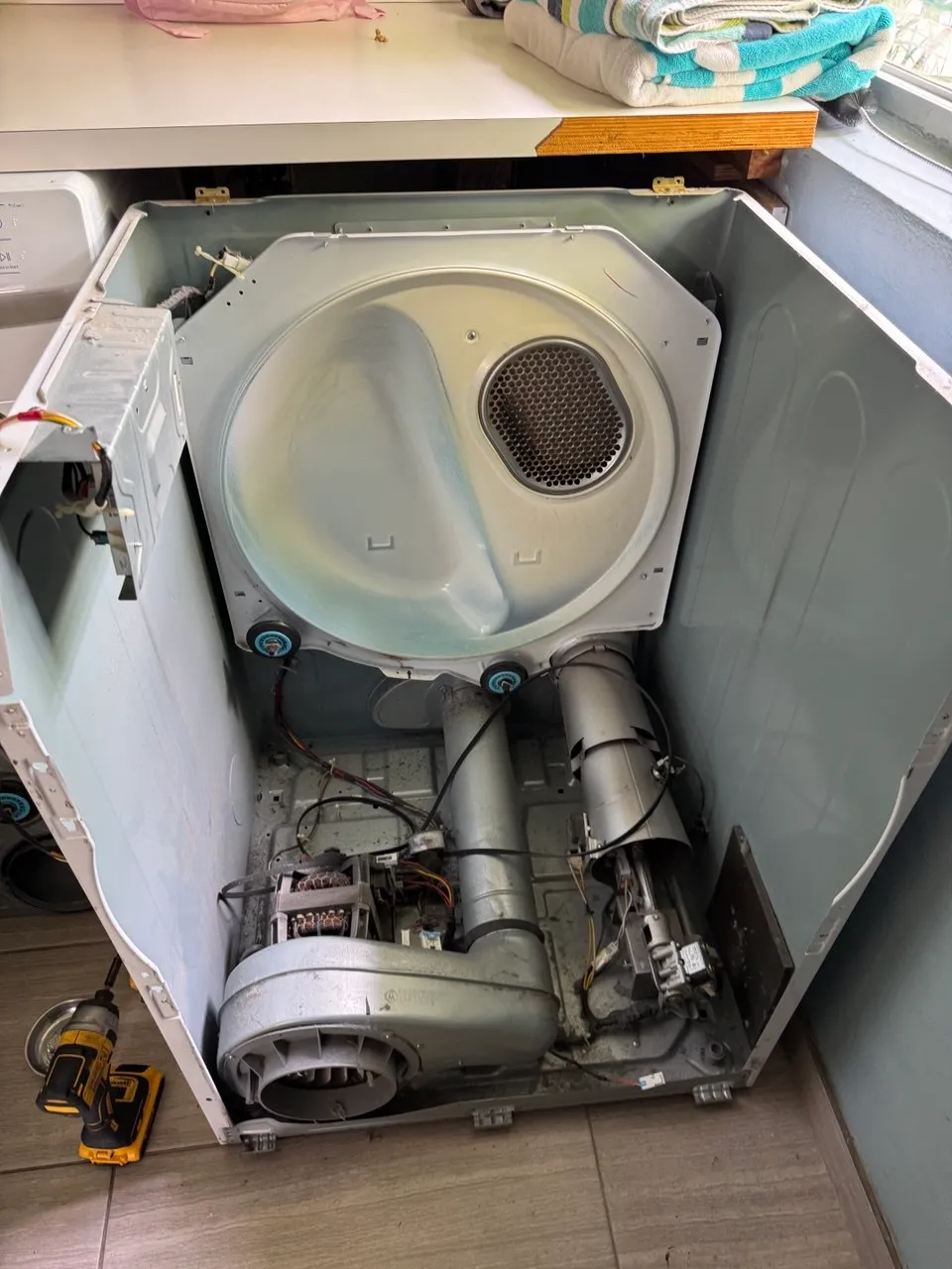 Dryer taken apart by a window, drum and blower exposed