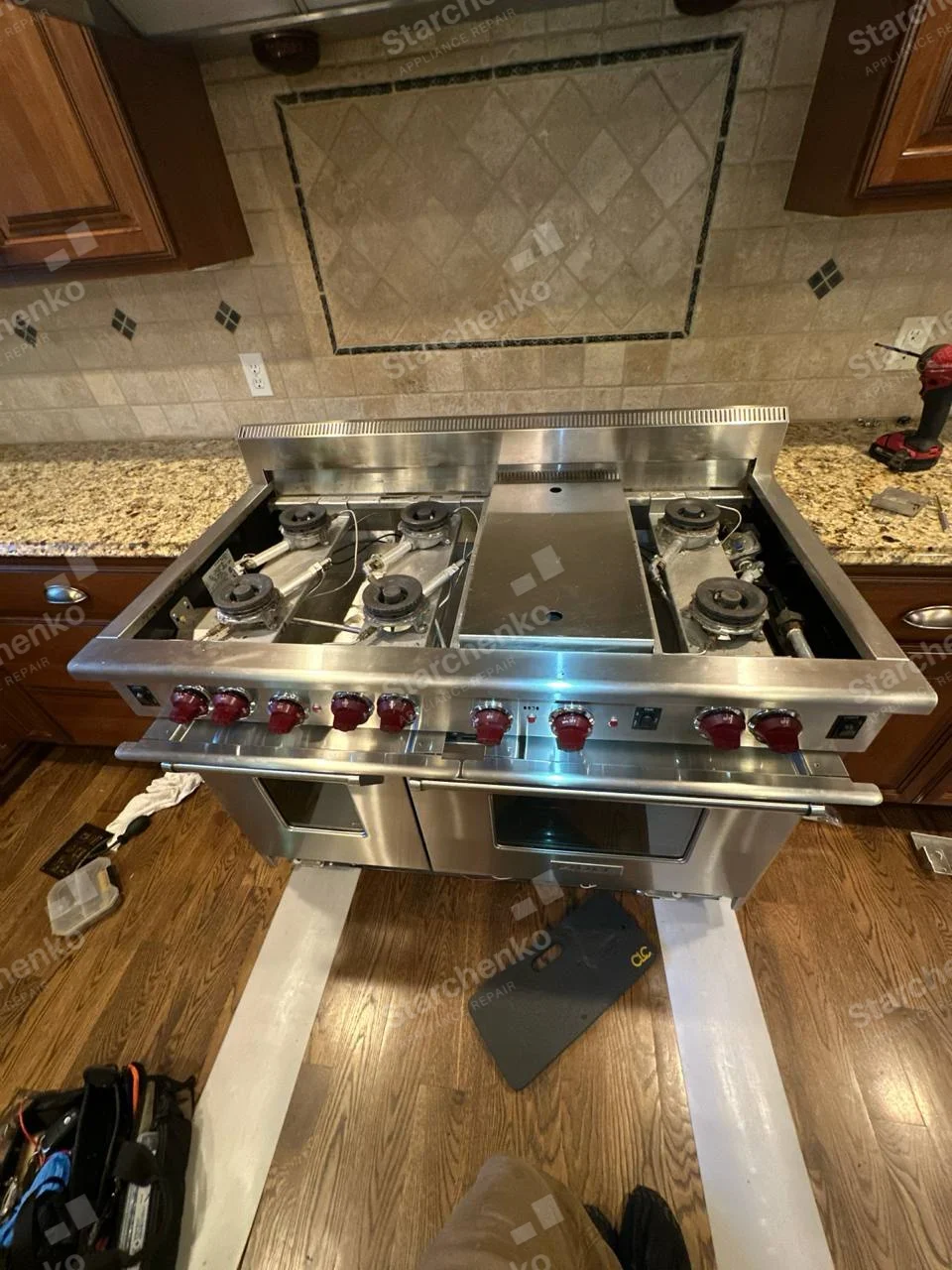 Wolf repair: Wide gas range with red burner knobs and cooktop disassembled.