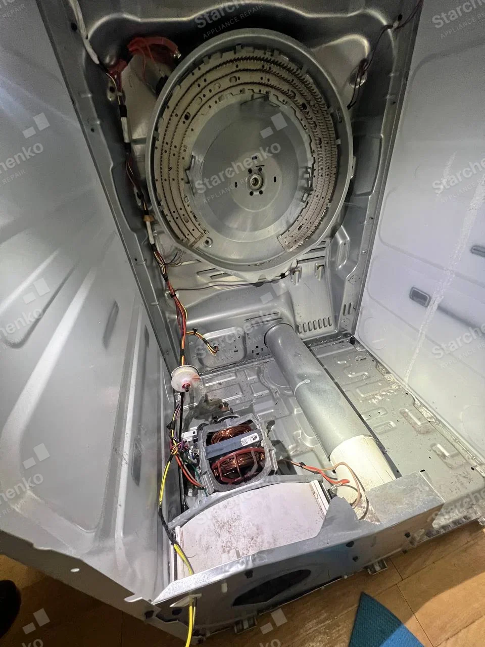 Maytag repair: Open dryer cabinet with rear circular heater mount and motor/blower assembly exposed, drum removed.
