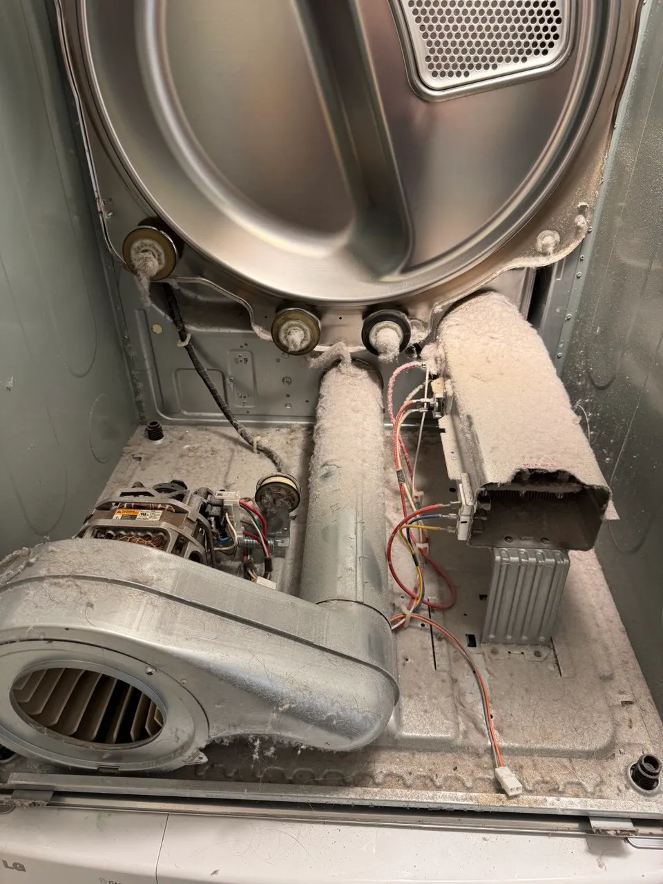 Inside of a dryer coated in lint around the motor and heat duct