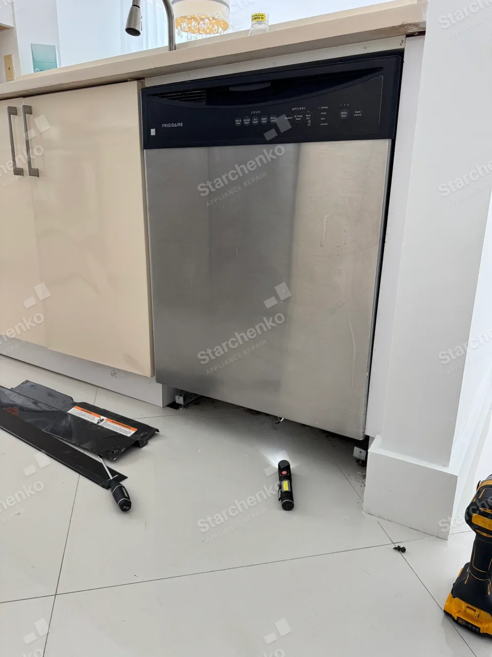 FRIGIDAIRE on left side of dishwasher control fascia, lower kick plate removed for access.
