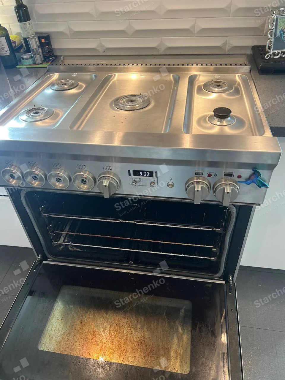 LG repair: Gas cooktop burner rings and oven cavity open with burner caps/grates removed, stainless freestanding range.