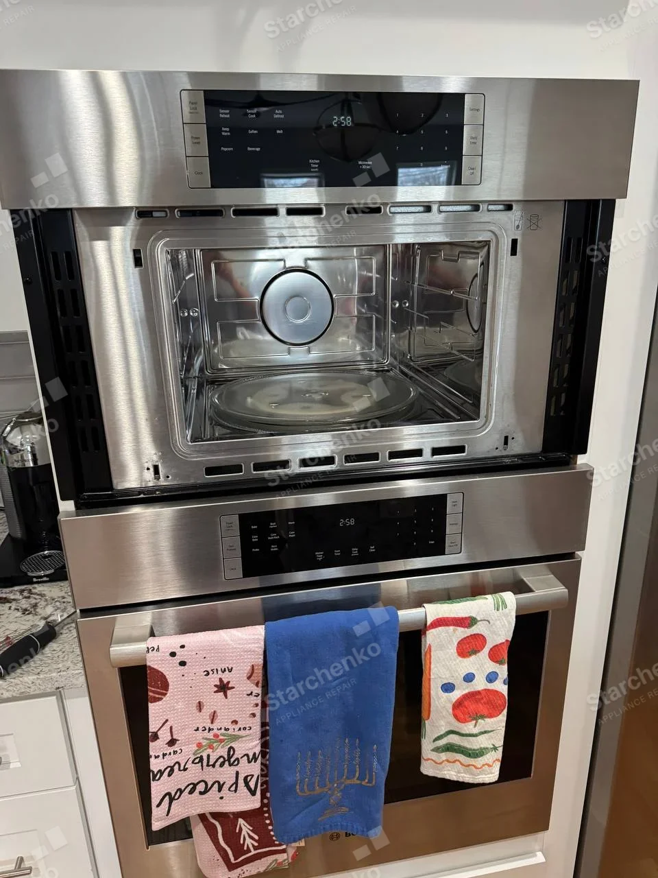 Samsung repair: Upper built-in microwave cavity exposed with turntable visible and front door/trim removed, oven below remains closed.